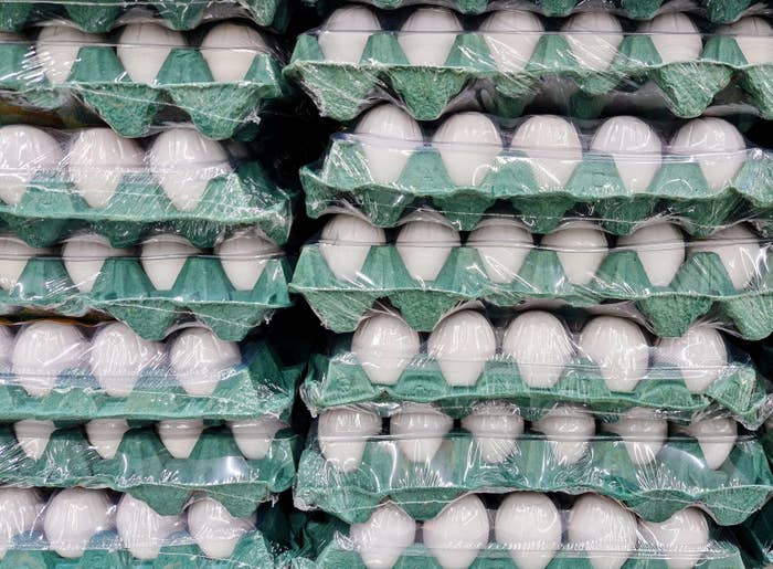 Stacks of egg cartons wrapped in plastic, organized in a store setting
