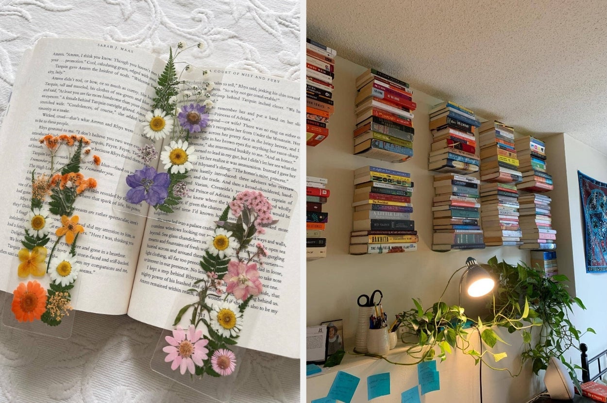 Pressed flowers on an open book beside a wall with colorful, stacked bookshelves and a desk with plants and notes