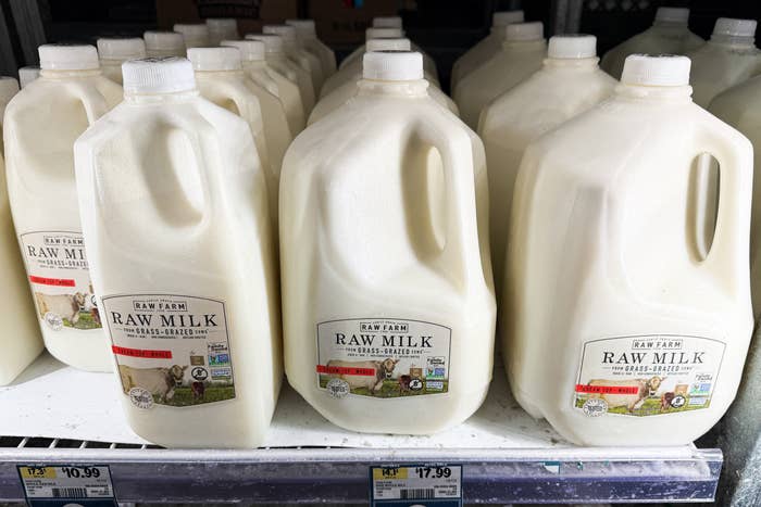 Shelves filled with gallon jugs of raw milk, labeled &quot;Raw Farm,&quot; featuring grass-fed sourcing information