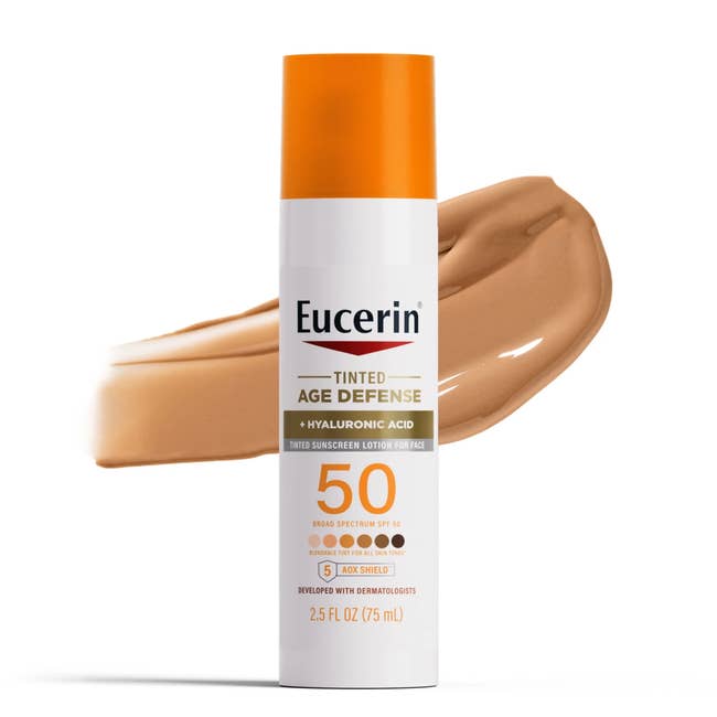 Eucerin Tinted Age Defense sunscreen with hyaluronic acerb  SPF 50, displayed with a swatch of its colour  successful  the background