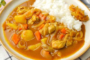カレーライスの皿に盛られた具沢山のチキンカレーとライスがテーブルに置かれている。