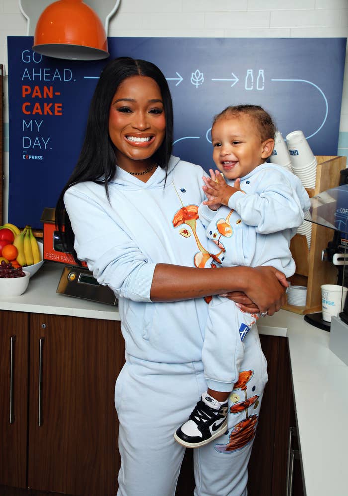 Keke Palmer in a casual outfit holds her son at a pancake-themed event
