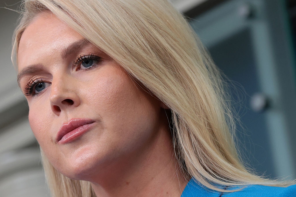 A person with long blonde hair looks thoughtful in a blue attire in a public setting