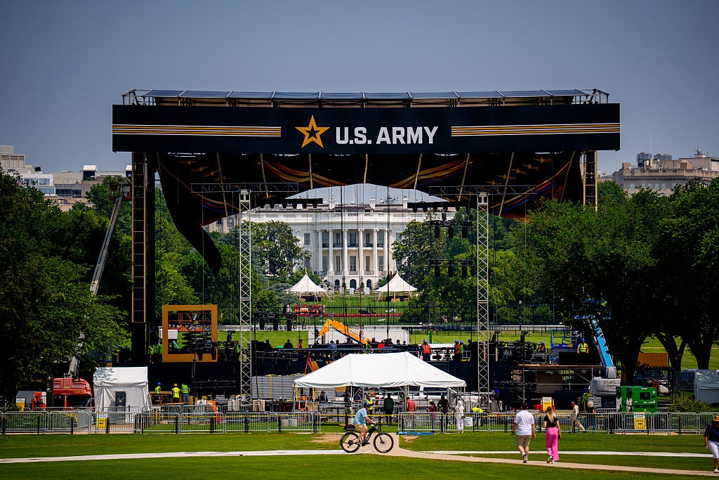 Stage setup with a U.S. Army banner in front of the White House, with people walking nearby and construction underway