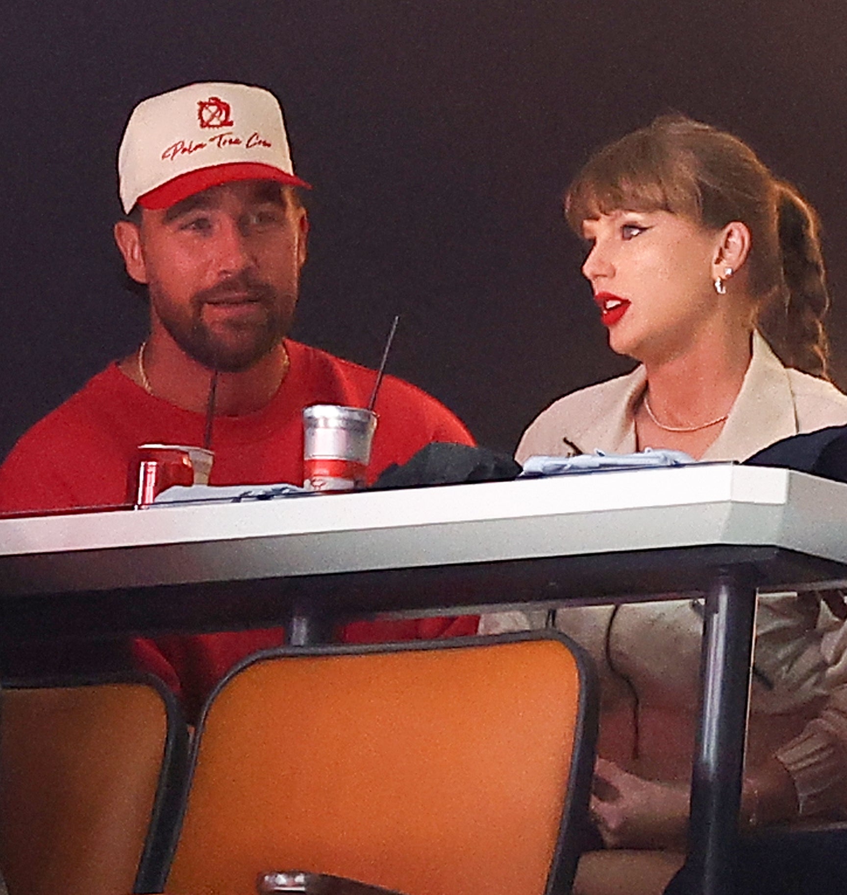 Travis Kelce and Taylor Swift sit at a table