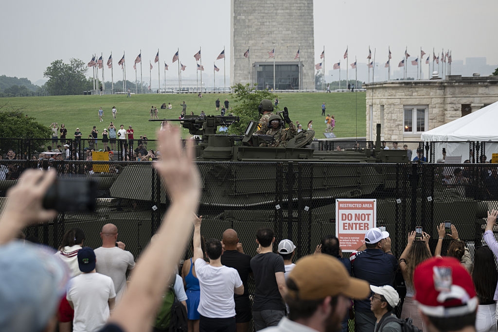 Tank displayed near Washington Monument, behind a fence with spectators photographing, during a public event. Do Not Enter sign visible