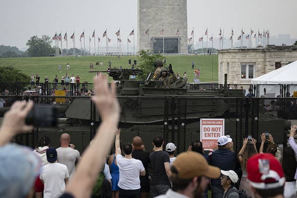 Tank displayed near Washington Monument, behind a fence with spectators photographing, during a public event. Do Not Enter sign visible