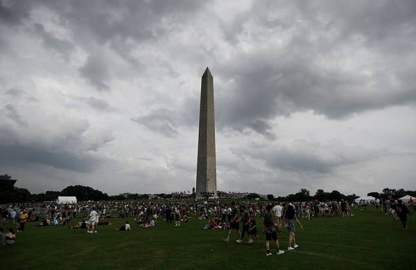 Crowd gathers near the Washington Monument under a cloudy sky