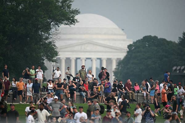 A large group of people gathers in a park near the Jefferson Memorial, enjoying a public event or sightseeing