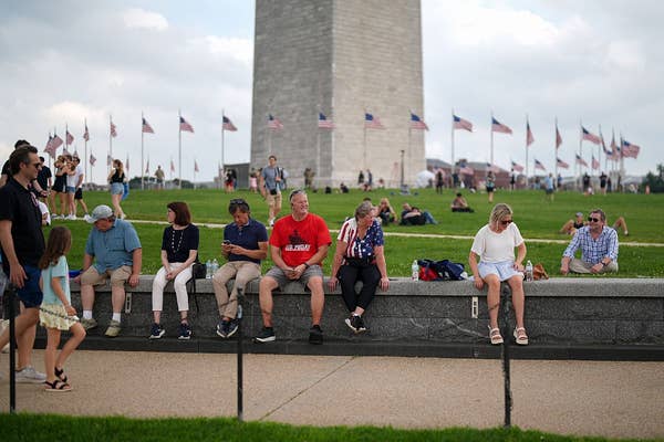 People sitting by the Washington Monument, flags in the background, enjoying a relaxed day outdoors