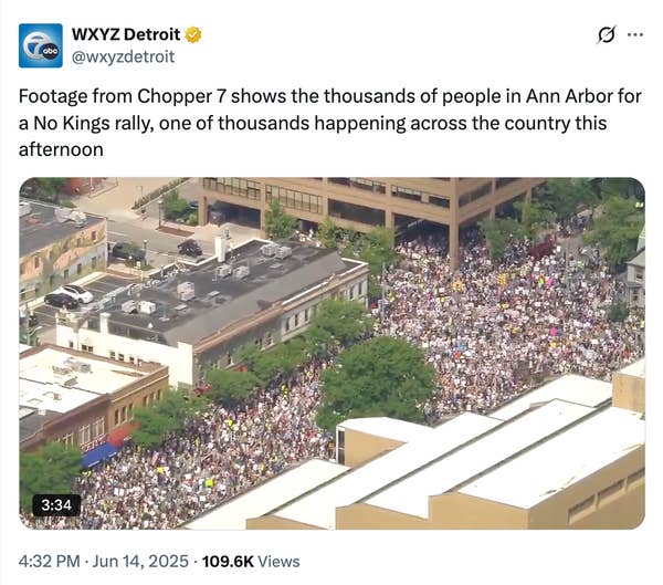 Aerial view showing a large crowd rallying in Ann Arbor for a &quot;No Kings&quot; protest. Dense gathering fills streets, seen from above