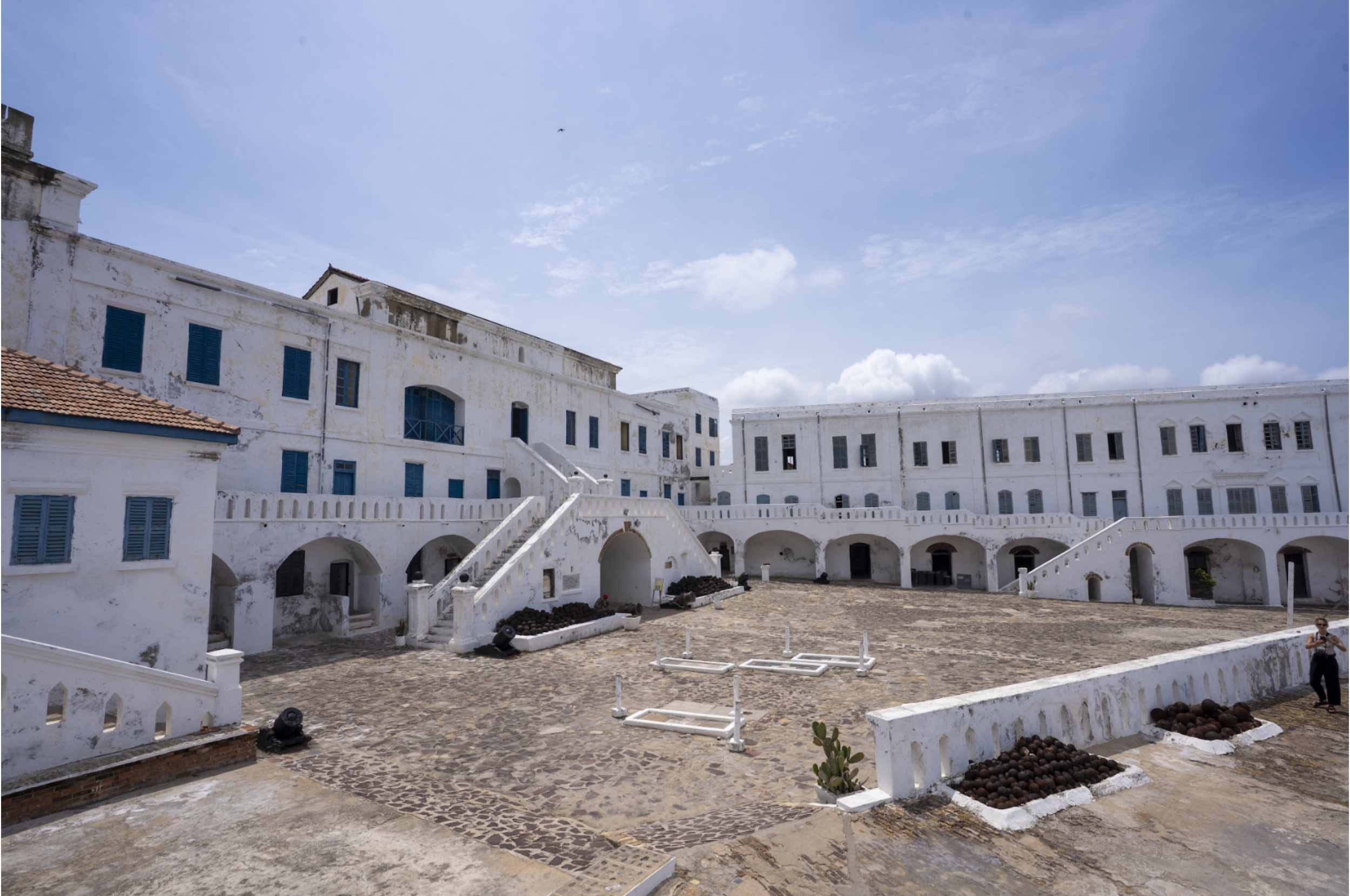 Historic coastal fortress with whitewashed walls and an open courtyard under a clear sky, suggesting a serene travel destination