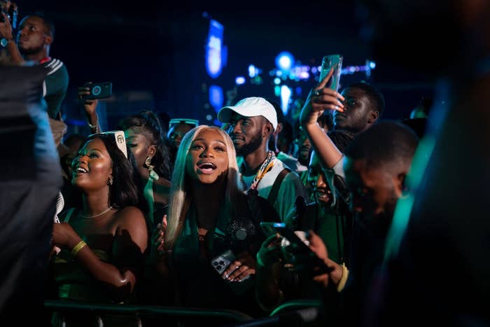 Concert crowd enjoying a live performance, with people holding phones and cheering energetically