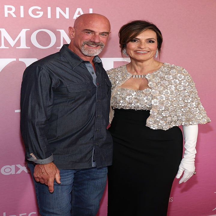 Two people on a red carpet. One wears a denim shirt, the other a black outfit with a sequined top and long white gloves