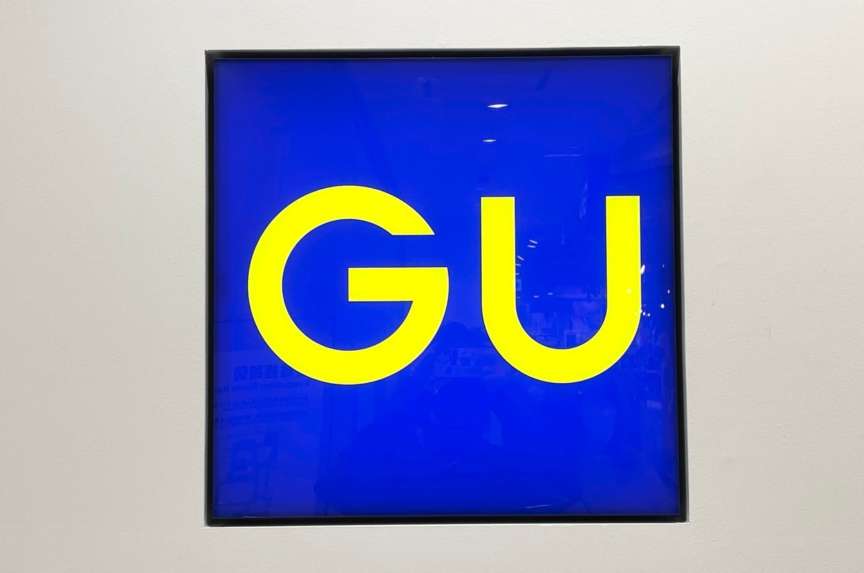GU store sign with bold yellow letters on a blue background
