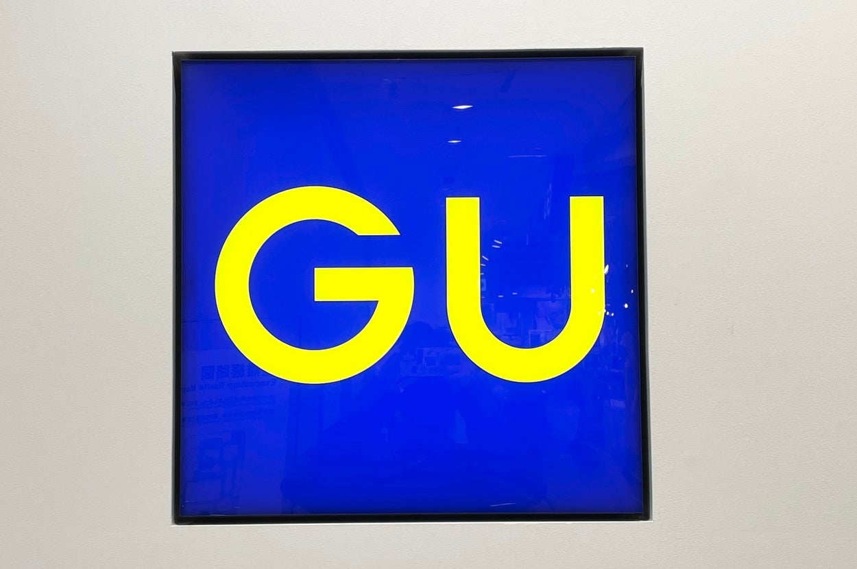 GU clothing store sign with bold yellow letters on a blue background