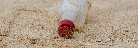 砂浜に落ちている蓋の付いたプラスチックボトル。環境問題を示唆するビーチのゴミ。