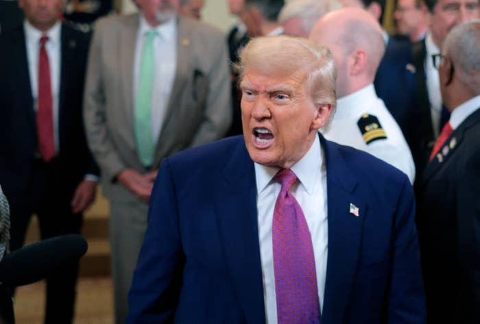 A person in a suit with an expressive face surrounded by others in formal attire