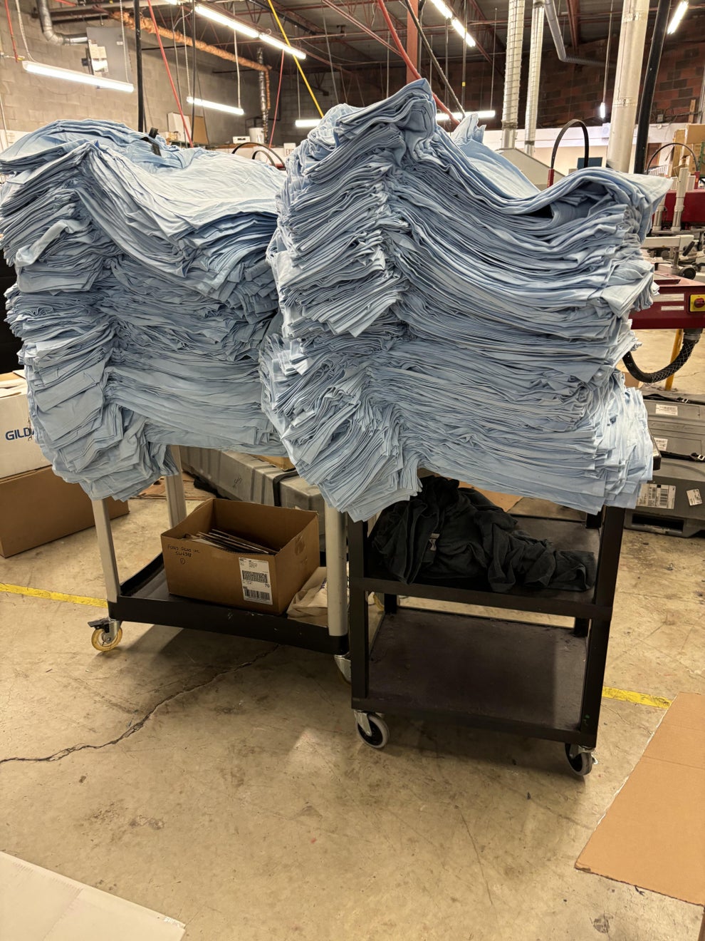Stacks of folded clothing on carts in a warehouse setting