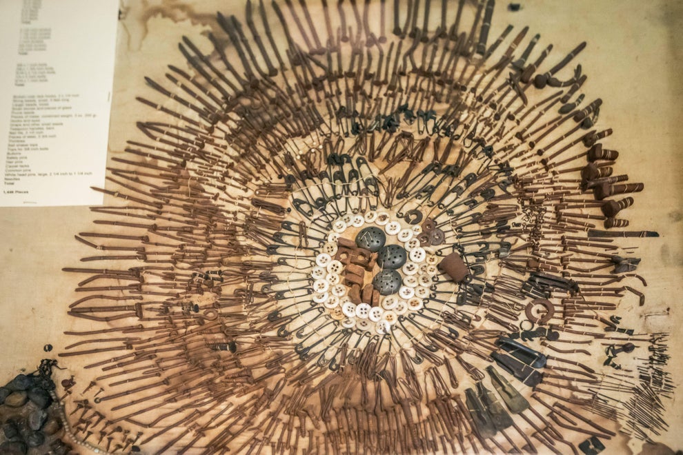 Aerial view of a circular arrangement of various rusted tools and metal objects displayed on a flat surface