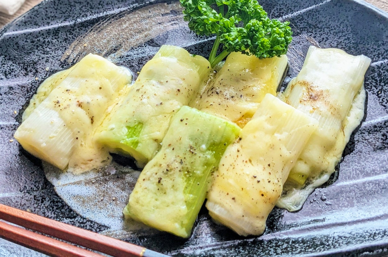 皿に盛られた焼きチーズのネギ巻き料理。トッピングにパセリが添えられている。
