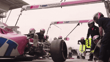 Pit crew swiftly changing tires on a Formula 1 car during a race pit stop, showcasing coordinated teamwork and efficiency