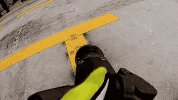 A firefighter's hose is being dragged across a concrete surface, spraying water with force, likely during a training exercise or emergency response