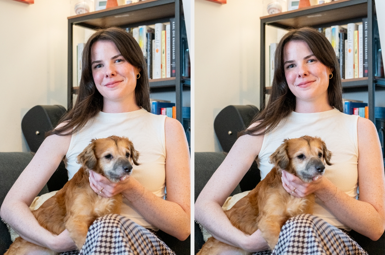 Person sitting on a couch, smiling, with a small, fluffy dog in their arms. Books are visible in the background on shelves