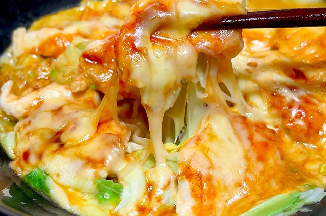 チーズがたっぷりのった料理を箸で持ち上げている。とろけたチーズが伸び、食欲をそそる。