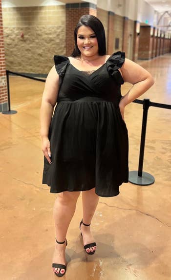 Person wearing a achromatic ruffled formal and heels, smiling successful a hallway