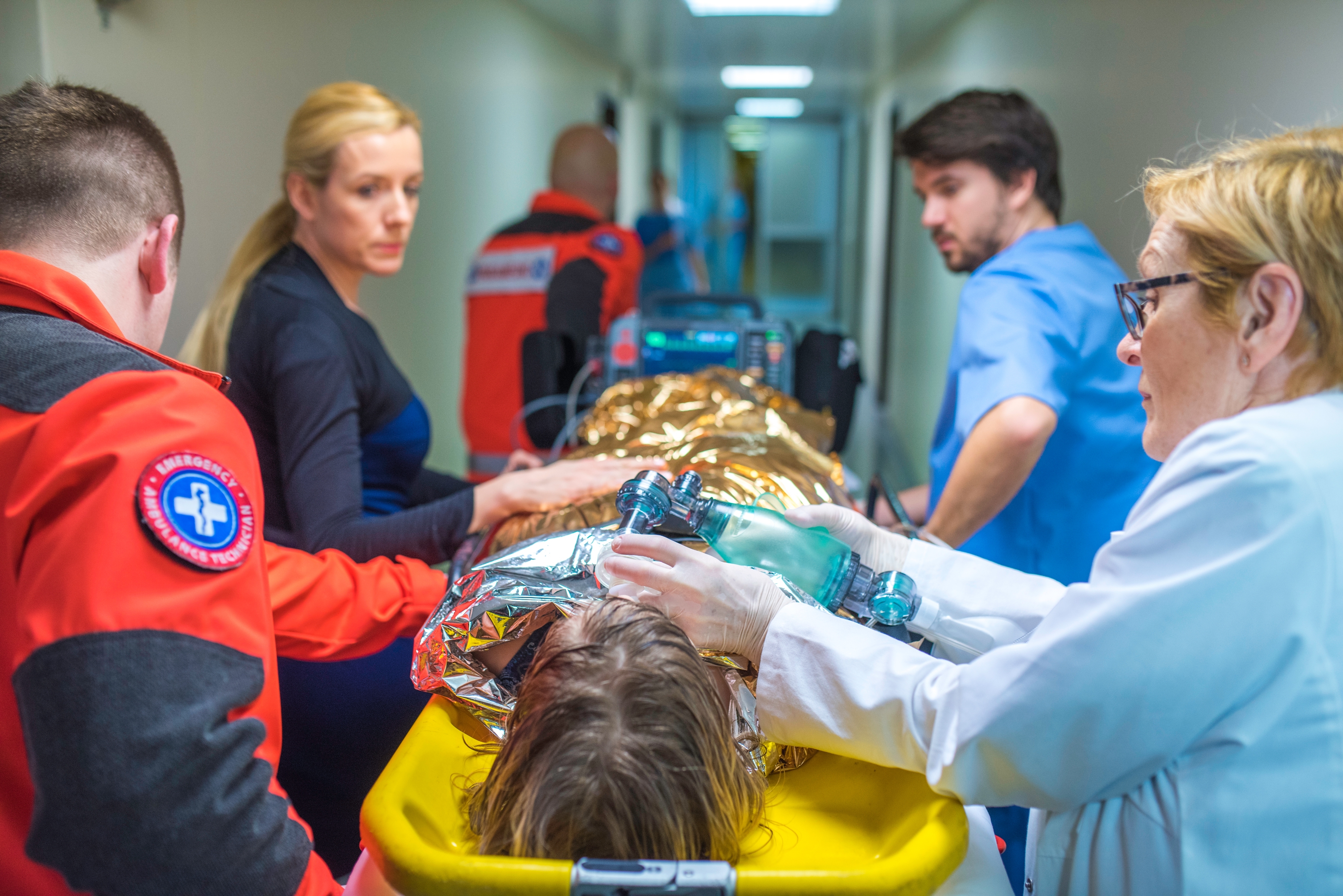 Medical team rushes a patient on a stretcher through a hospital corridor. Emergency staff are focused and assisting with medical equipment