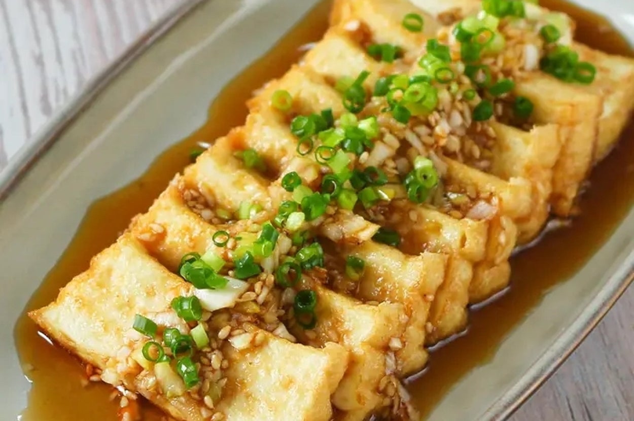 皿に盛られた揚げ豆腐にネギとソースがかかっている料理。