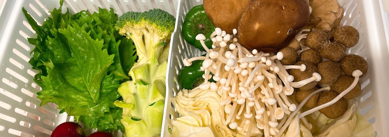 野菜とキノコがバスケットに入っている。左にブロッコリーとラディッシュ、右にエノキダケとシイタケなど。