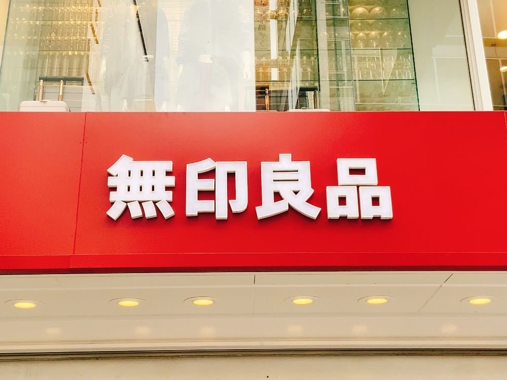 赤い看板に「無印良品」の白い文字が表示されています。店舗の外観。