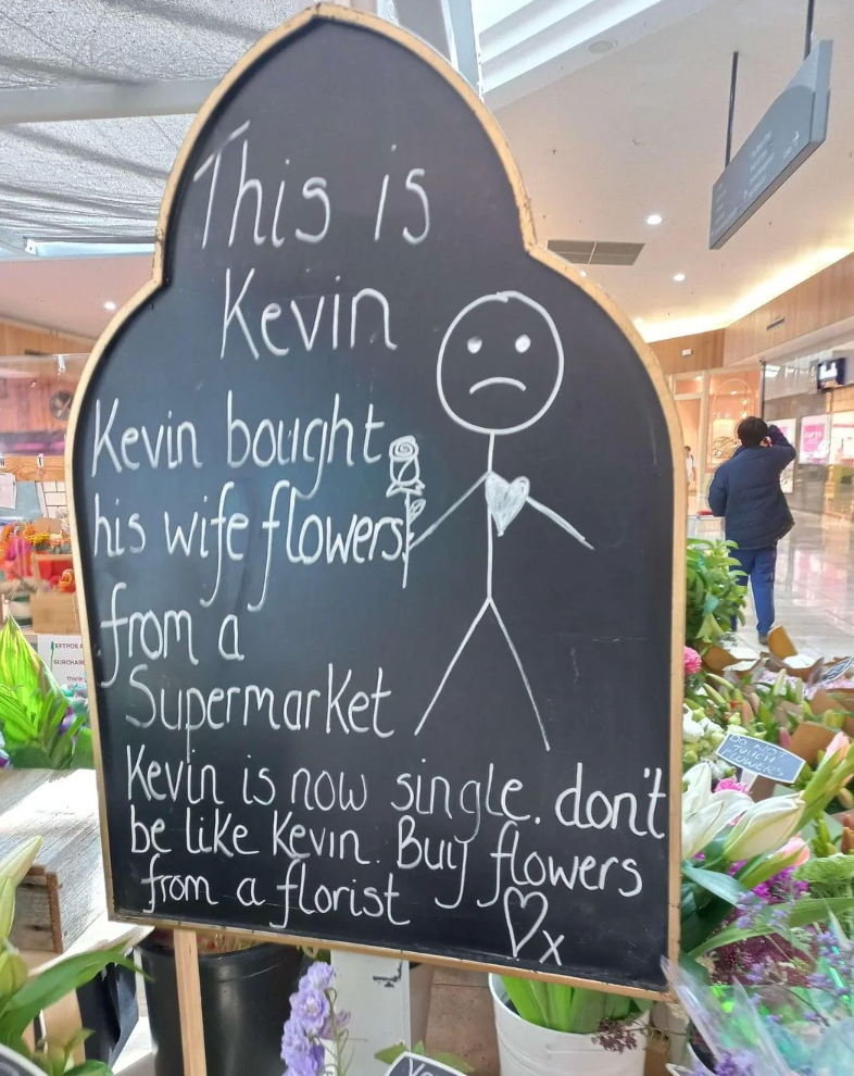 A chalkboard motion   with a instrumentality   fig  and substance   urging radical   to bargain  flowers from a florist, humorously suggesting Kevin mislaid  his spouse  by buying supermarket flowers