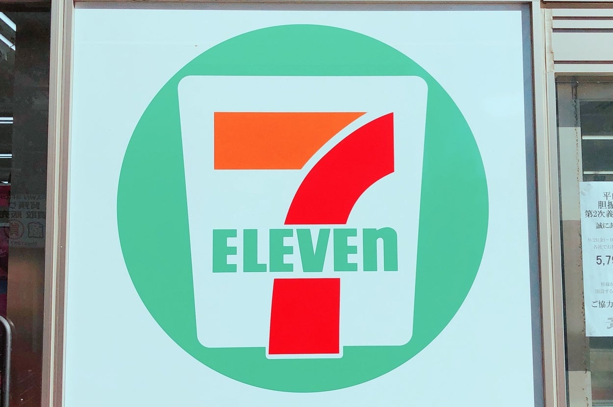 セブンイレブンの店舗外観。窓に大きなロゴと商品宣伝ポスターが見えます。