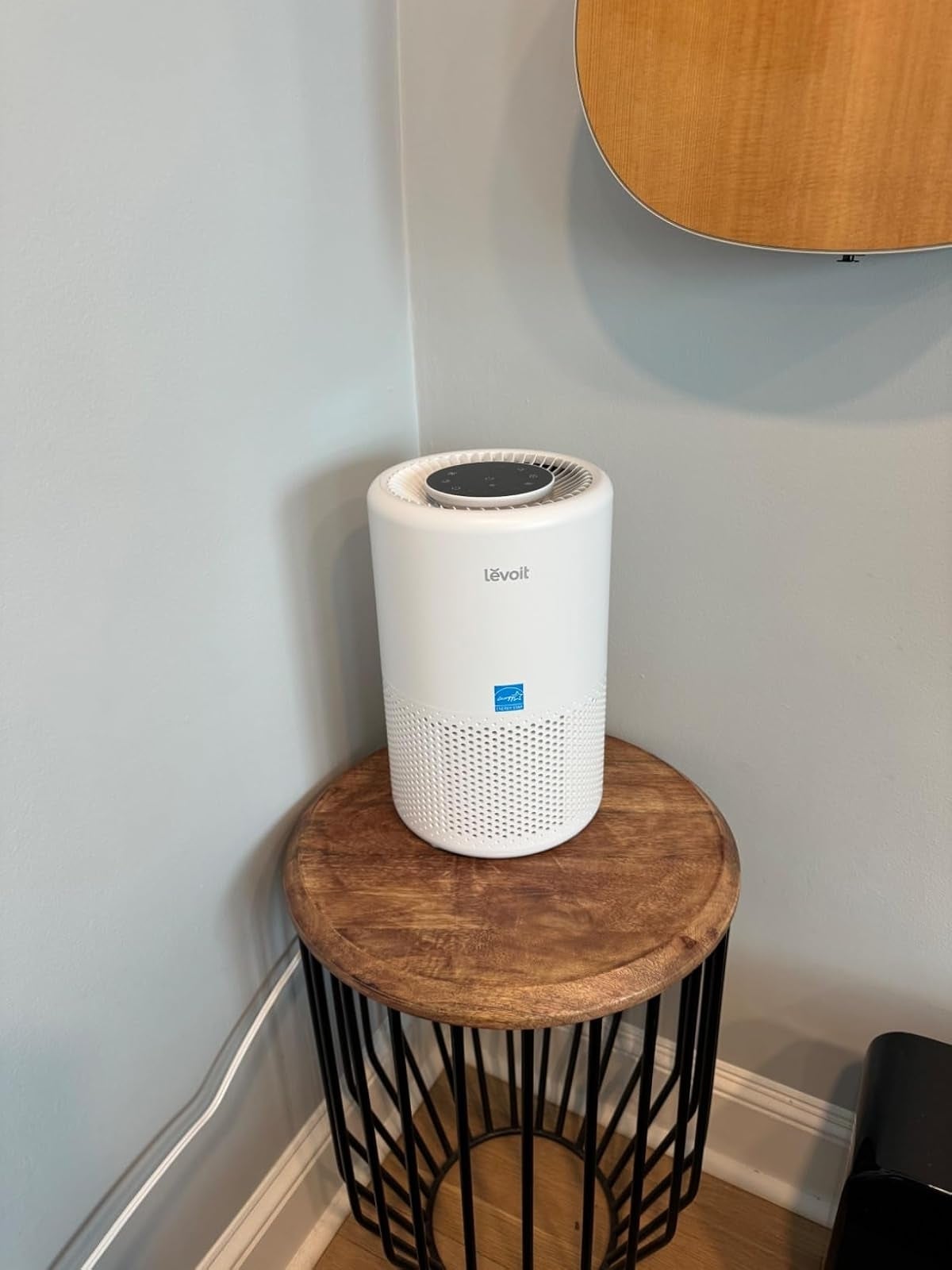 Air purifier connected  a circular  woody  array  adjacent  to a guitar hanging connected  the wall