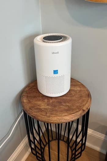 Air purifier connected a circular woody array adjacent to a guitar hanging connected the wall