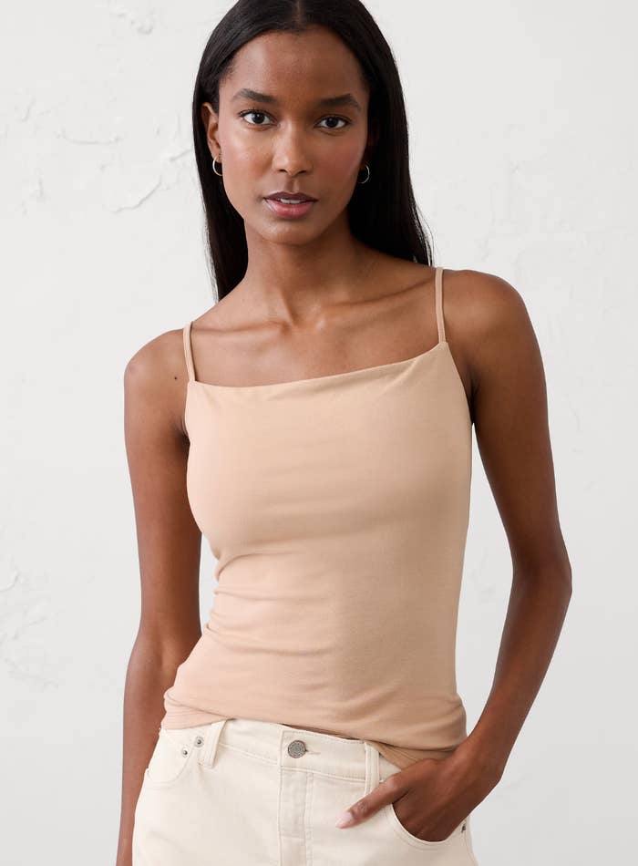 Person successful  a fitted camisole and jeans, posing confidently