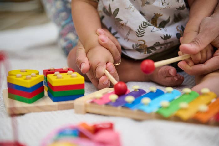 Child and big  playing with a colorful xylophone and stacking toys connected  a brushed  mat