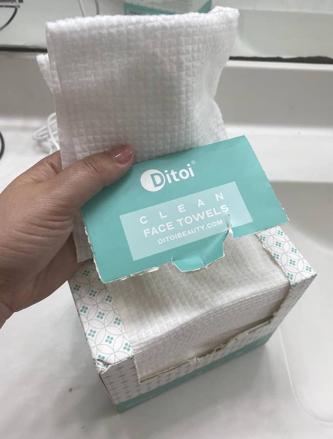 Hand holding a container  of Ditoi cleanable  look   towels, showing the packaging plan  and branding