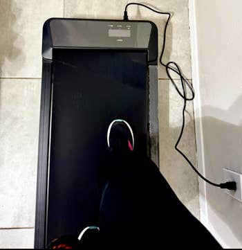Person walking connected a sleek, compact treadmill successful a location setting, plugged into a adjacent partition outlet