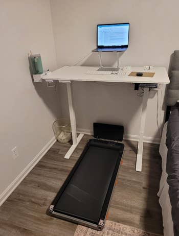 Treadmill table setup with a laptop connected a raised stand, keyboard, mouse, and a cupful holder connected the side
