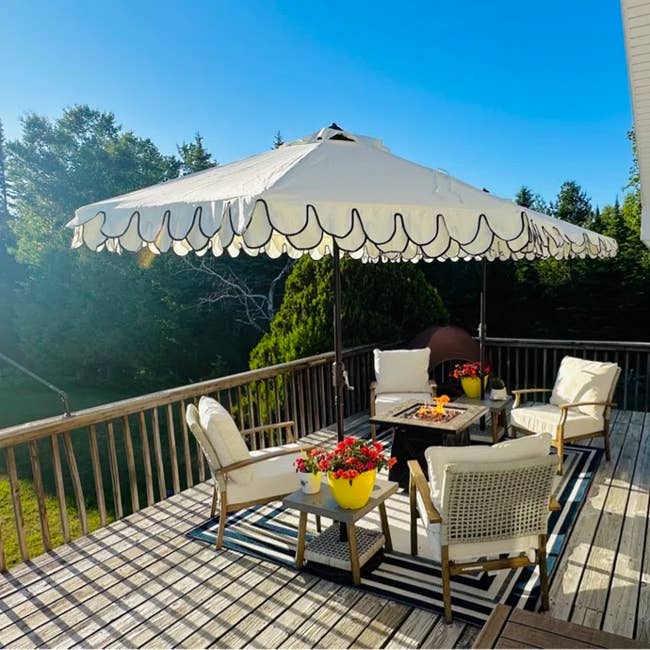 Outdoor patio acceptable   with cushioned chairs and a scalloped umbrella implicit    a occurrence  pit table, connected  a platform  with potted flowers