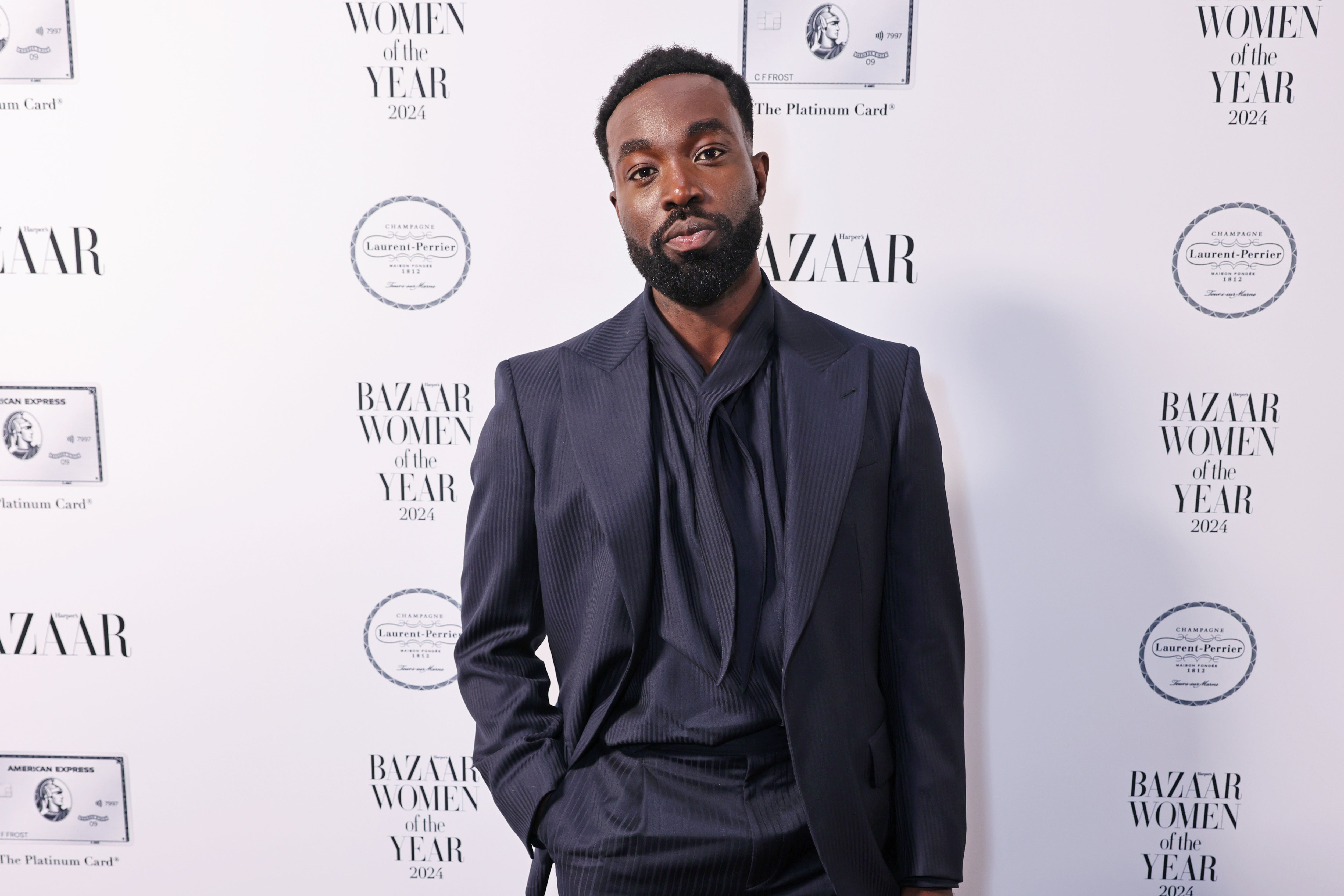 Paapa Esseidu in elegant suit at a red carpet event with "Bazaar Women of the Year 2021" logos on the backdrop