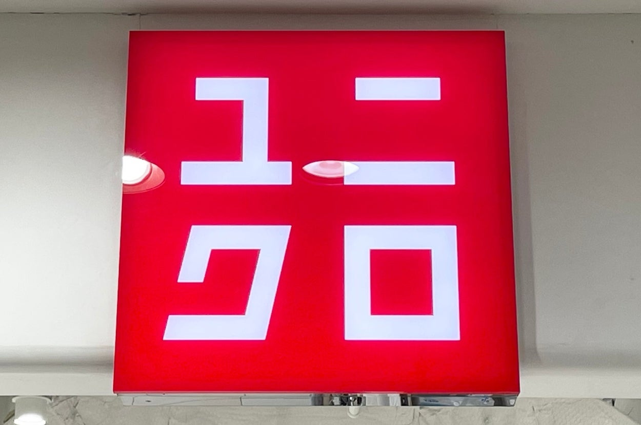 A square sign with Japanese characters resembling "ユニクロ" on a red background, often associated with a popular clothing brand