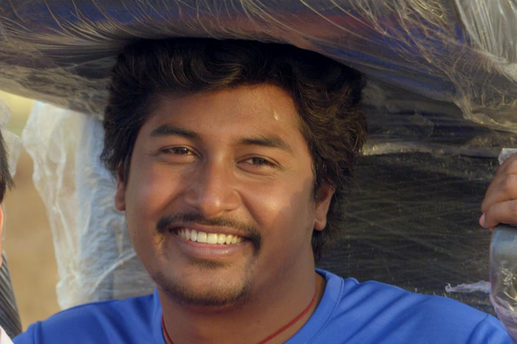 A person smiling while carrying a wrapped object on their head