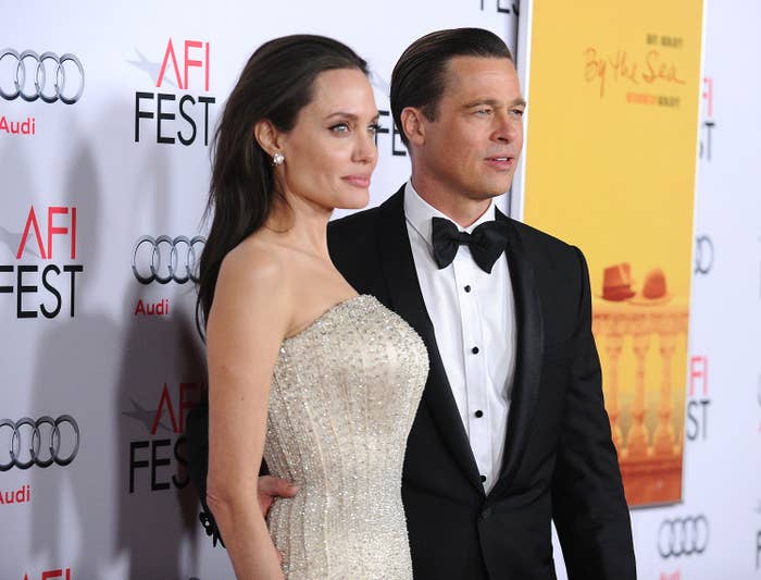 A woman in an elegant strapless gown and a man in a classic tuxedo pose together at a red carpet event, with AFI Fest signage in the background