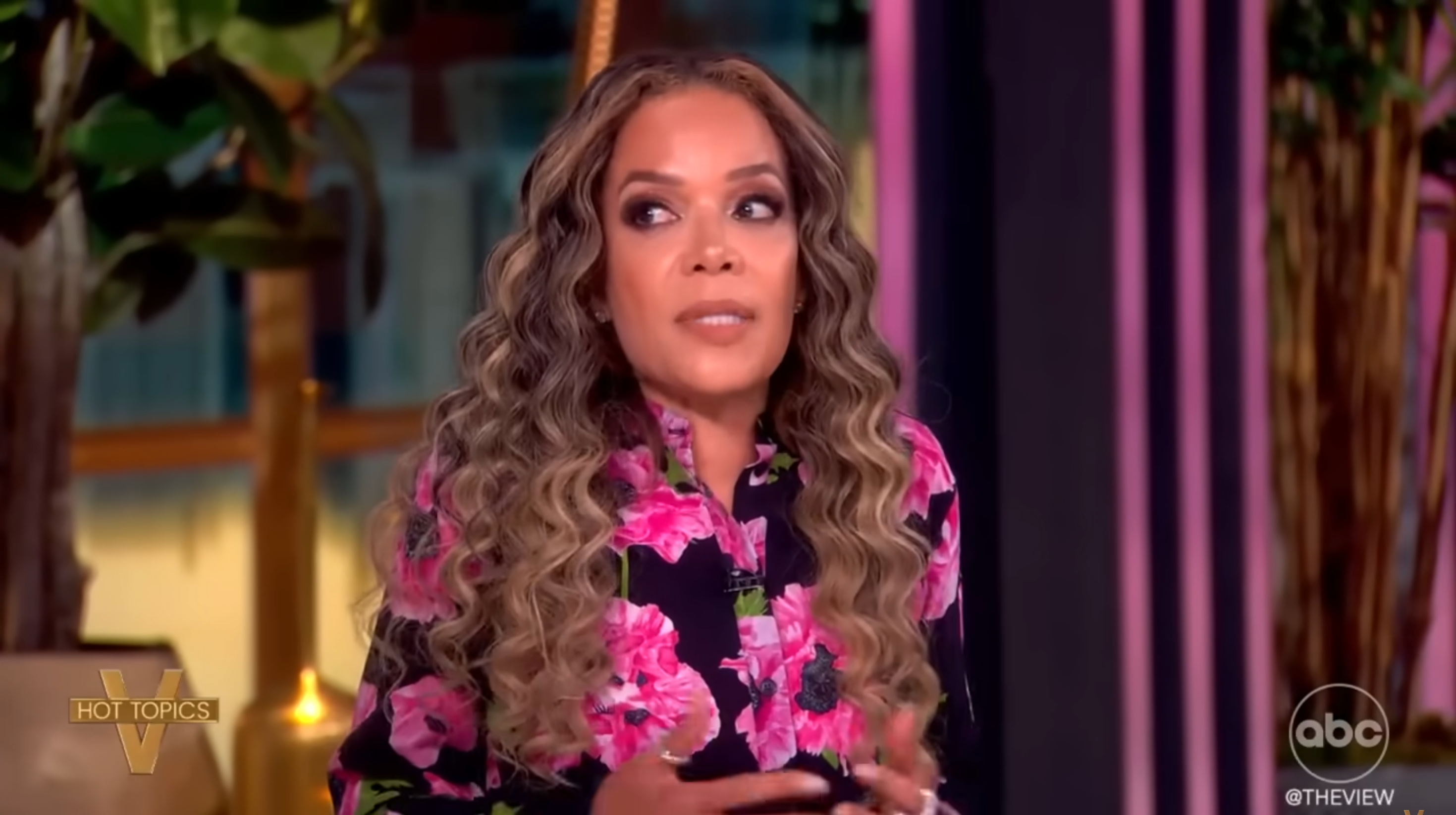 Person in floral top speaks during a talk show segment with "Hot Topics" and "The View" logos visible