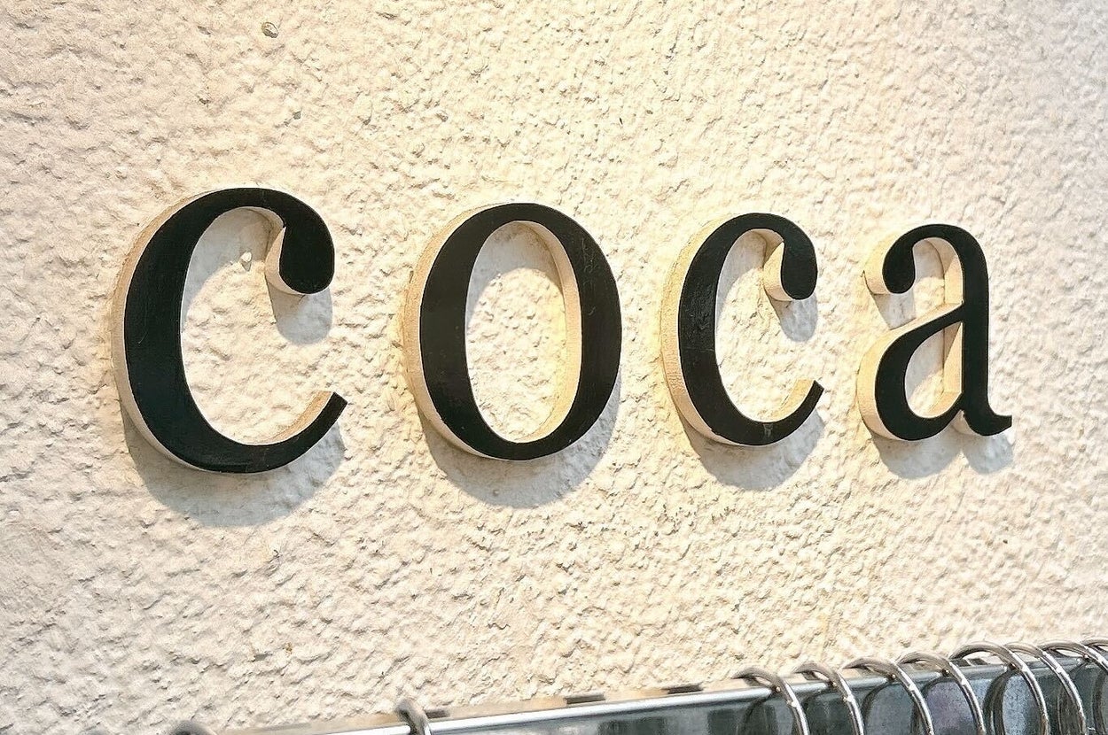 「coca」と書かれた壁の前にハンガーが並んでいる店内の様子。